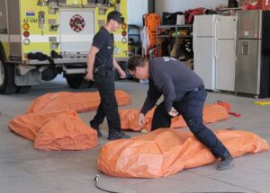Vernon Fire District Firefighters deploy practice fire shelters at the station.